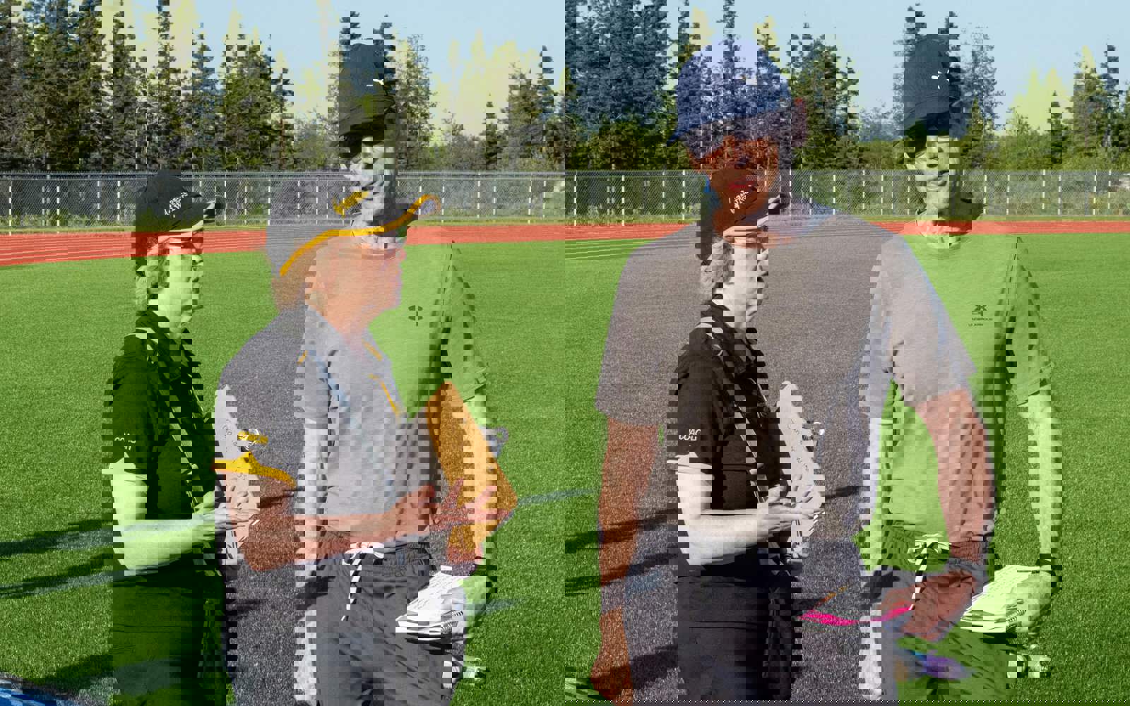 Three coaches and volunteers are standing on a bright blue track discussing amongst one another.