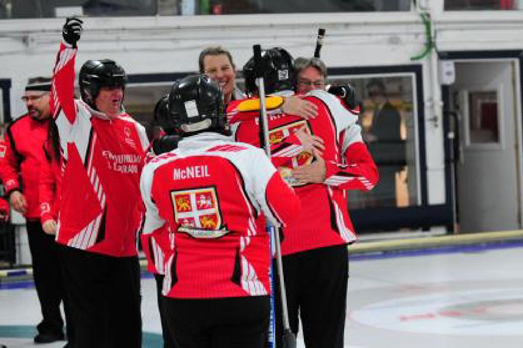 Group of people in hockey uniforms hugging each other on the ice 