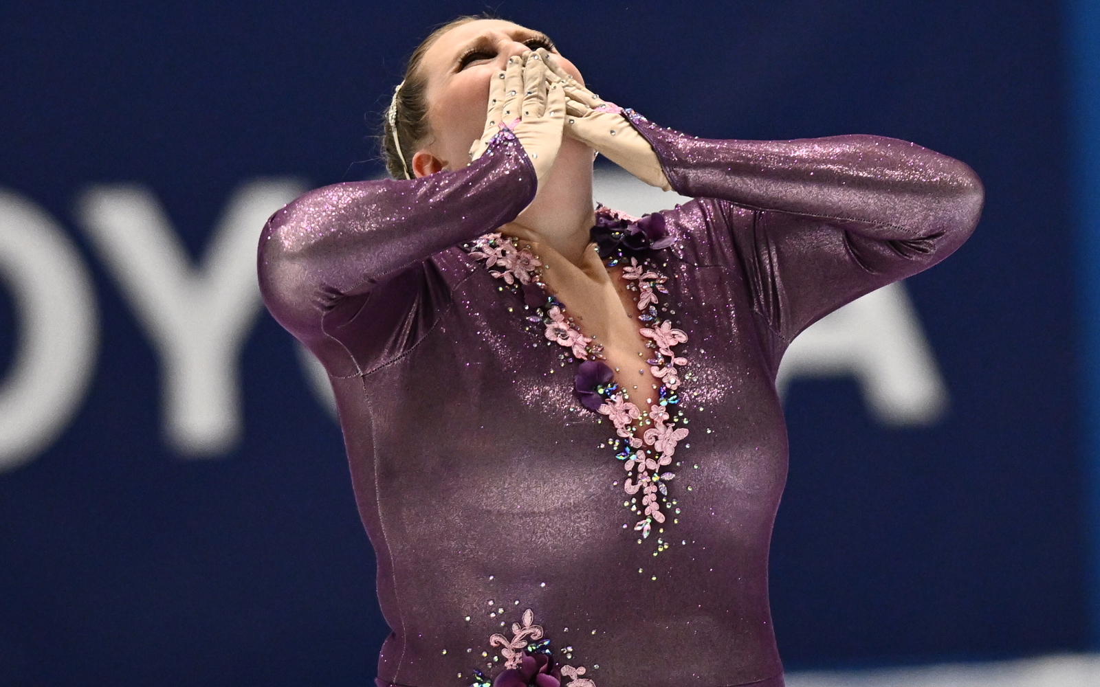 Woman in purple figuring skating blowing a kiss