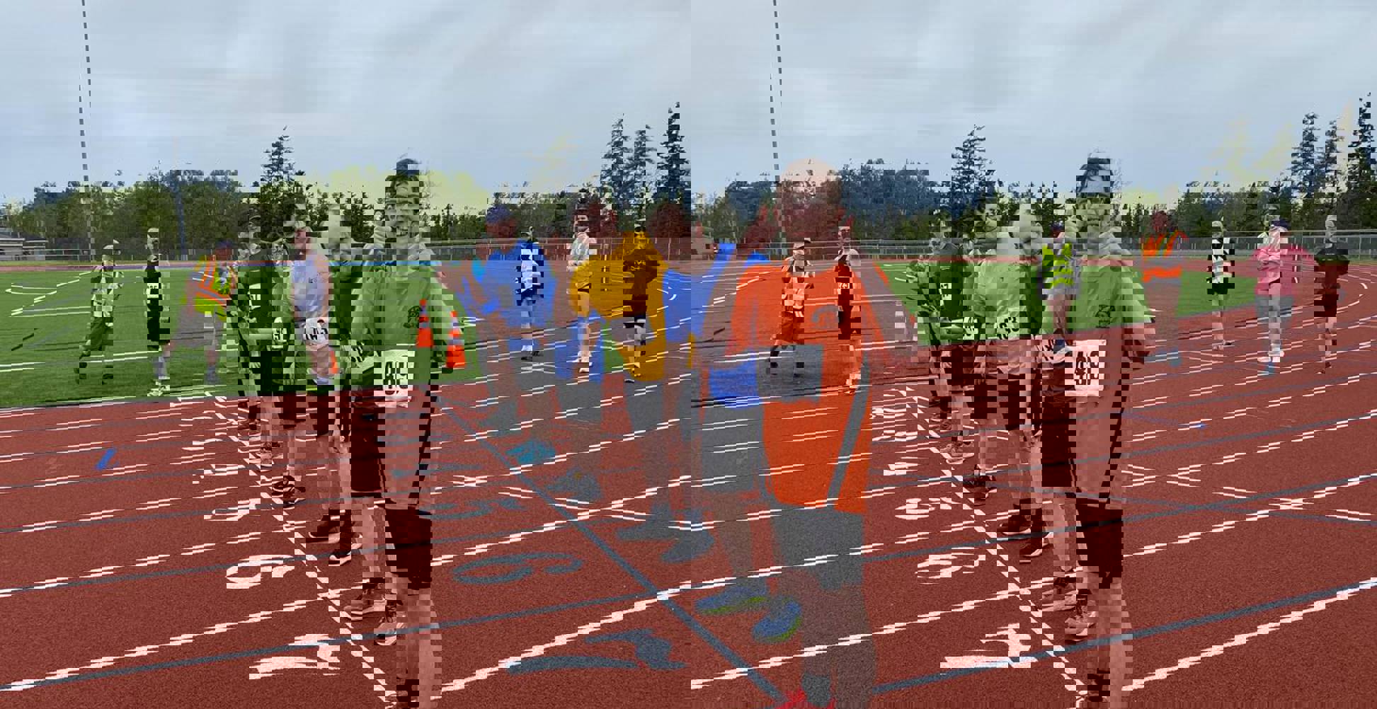 Diverse group of people standing on a race track getting ready to run a race. 