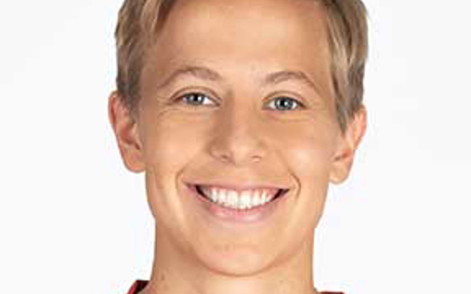 Headshot of a person with short blond hair wearing a Canada soccer jersey. 