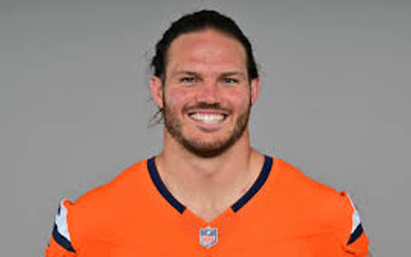 Headshot a man in an orange NHL jersey 
