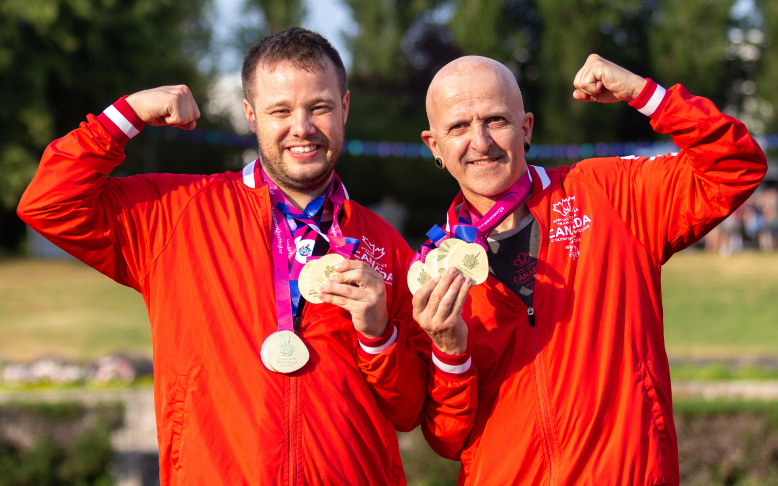 Two athletes in Team Canada uniforms with medals around their necks. 