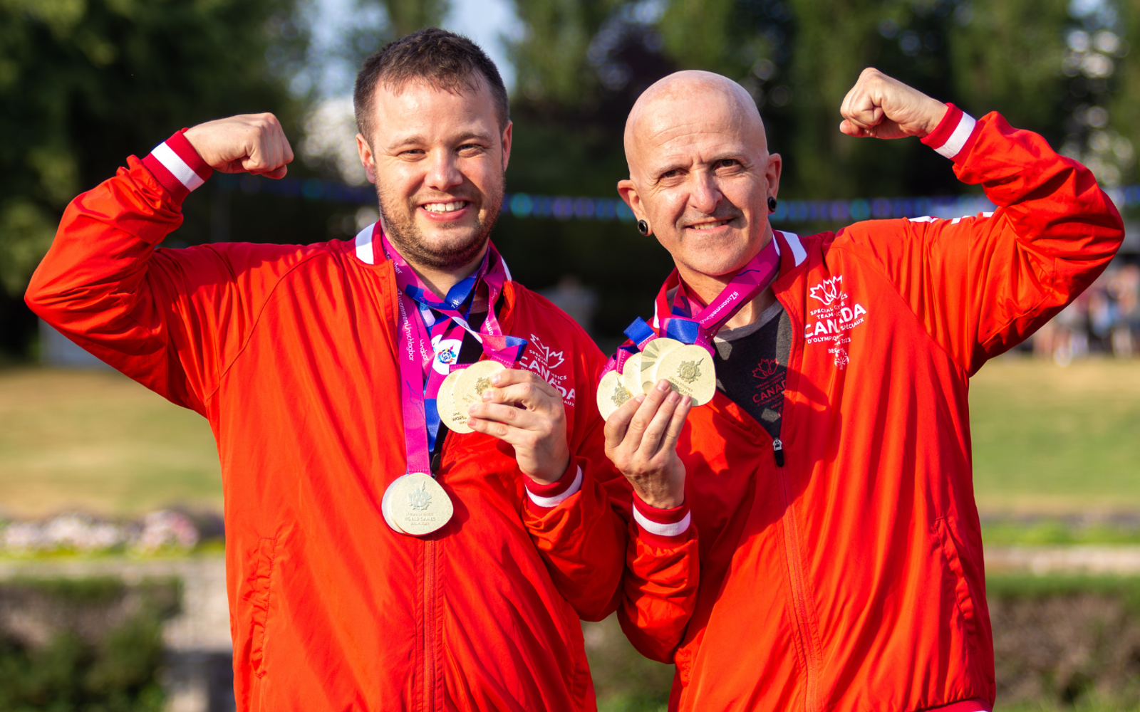 Two athletes in Team Canada uniforms with medals around their necks. 