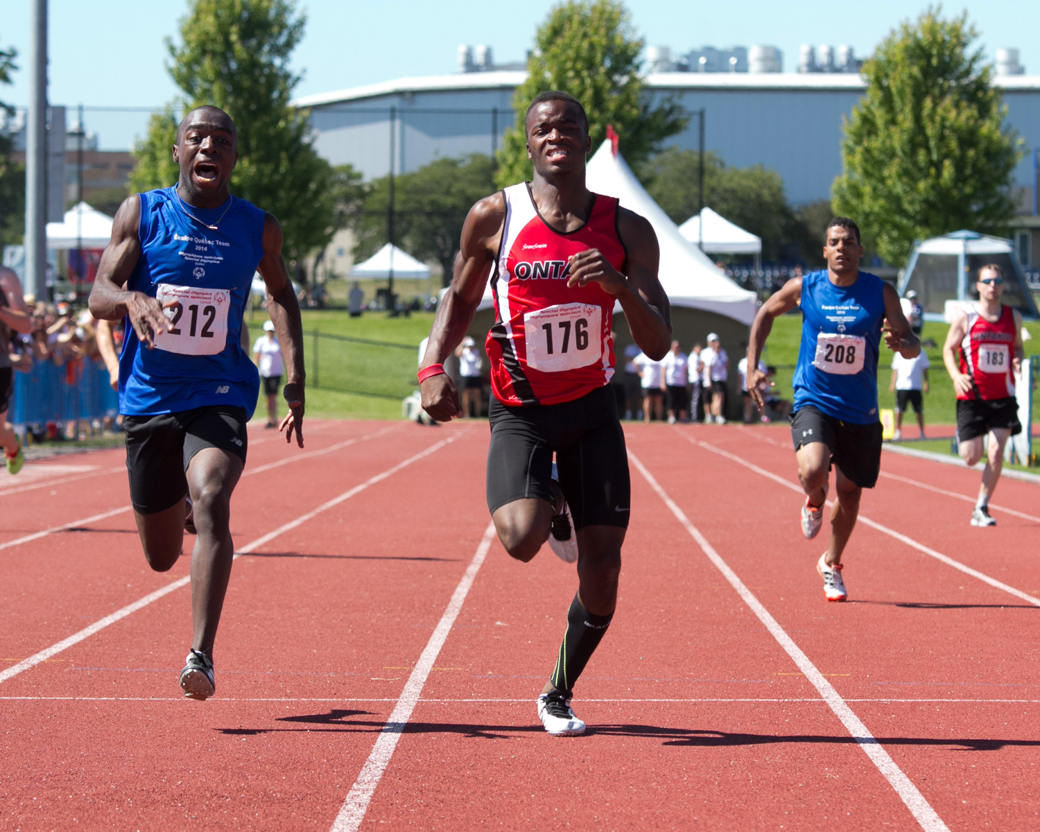 Two athletes running on a track. both are very focused on running. 