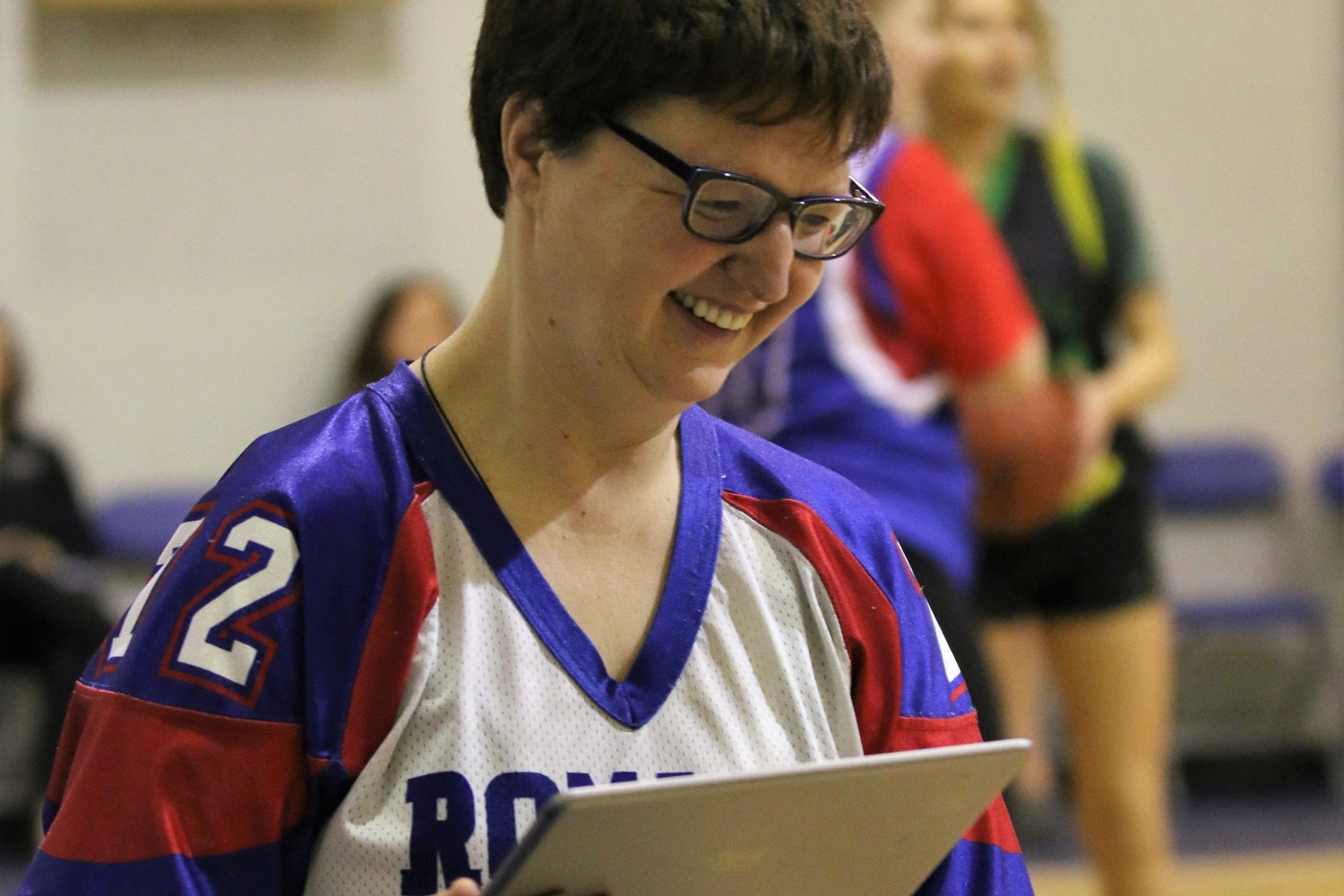 A closeup image of a volunteer holding an iPad. She is smiling and looking down.