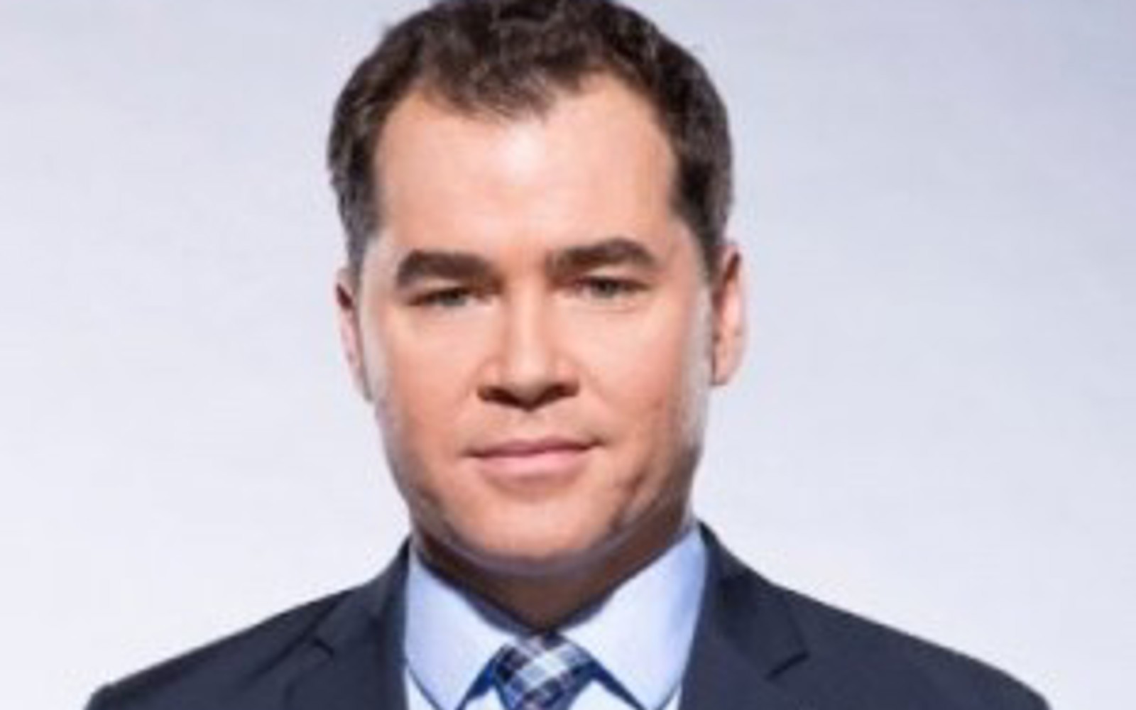 Man in blue suit, light blue shirt and blue plaid tie. 