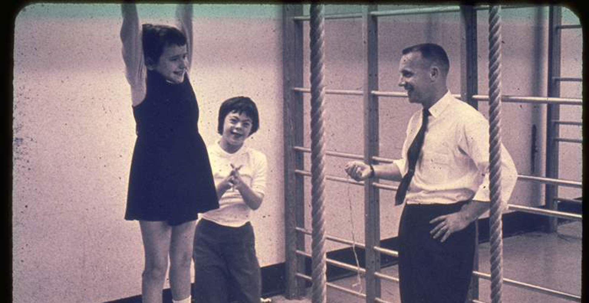 Two young children playing while a man in a suit stands beside them