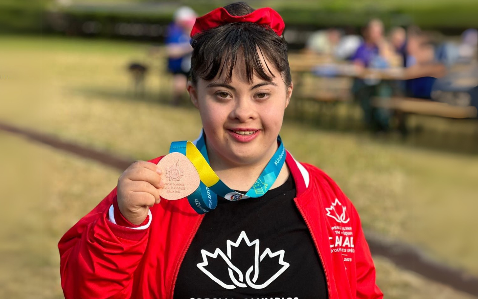 One athlete in Team Canada uniforms with medals around their necks. 