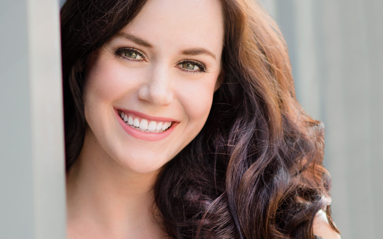 Headshot of a woman with dark culy hair wearing a pale green sequined top. 