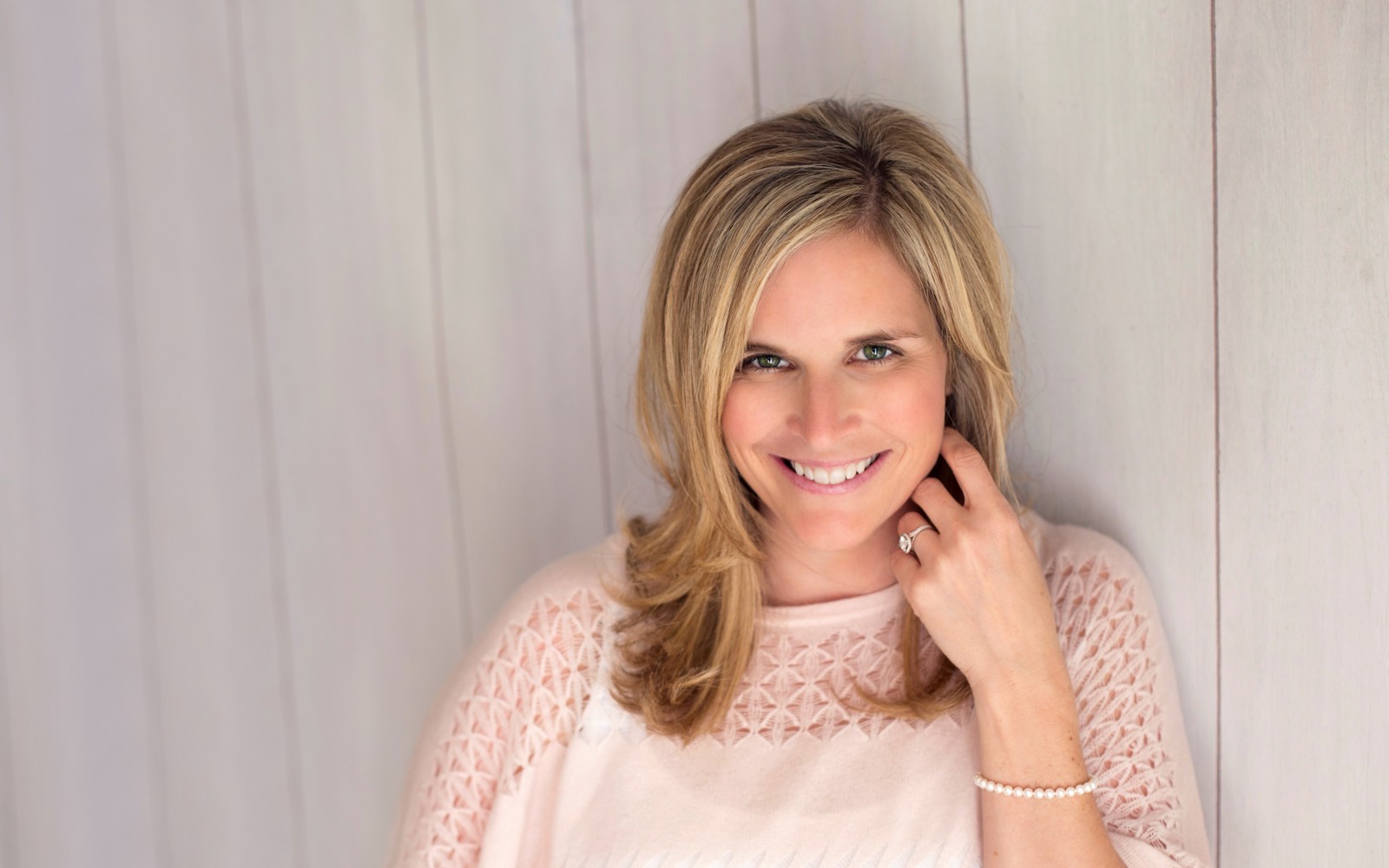 Portrait of a women with long blond hair wearing a white sweater. 