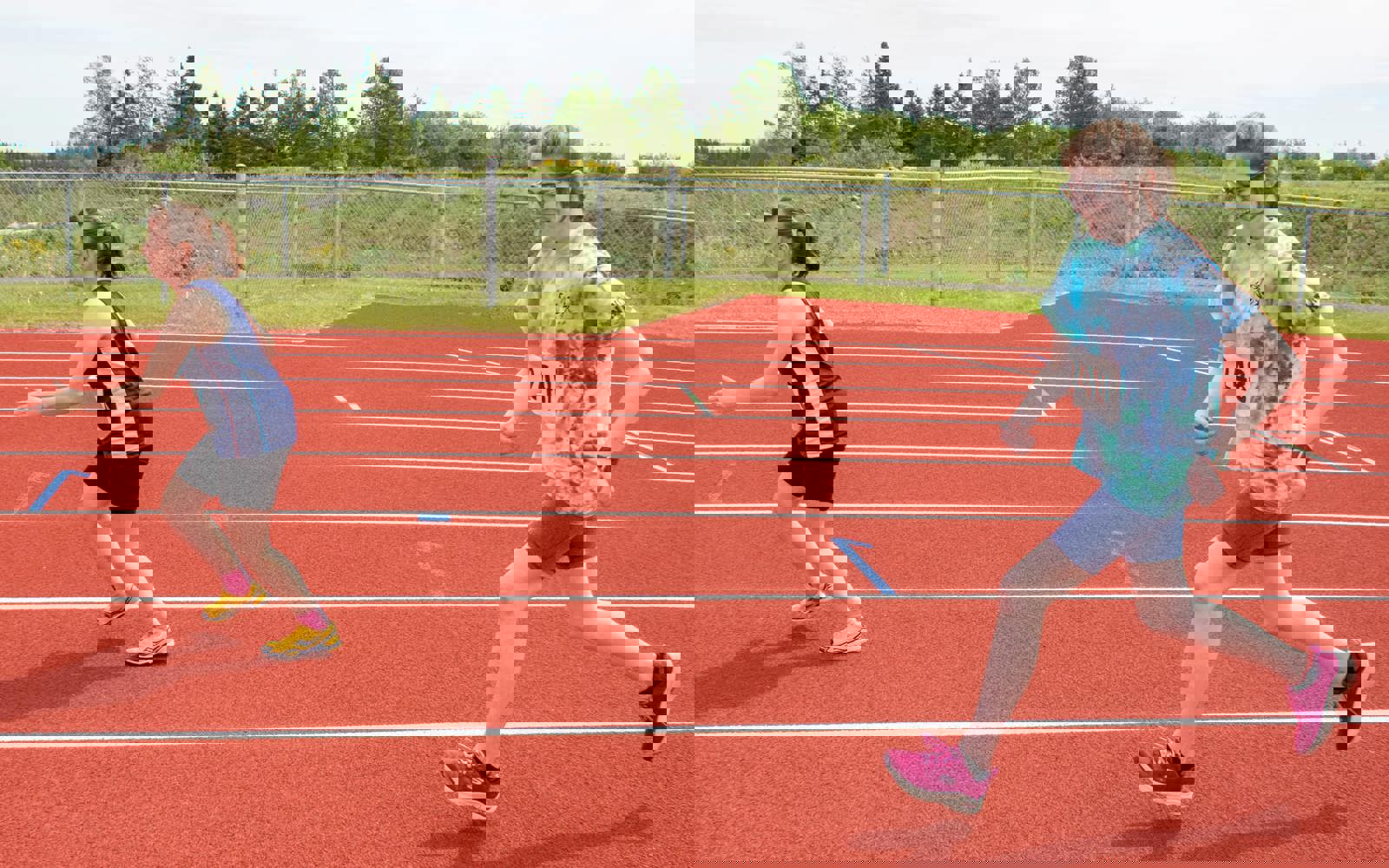An action shot photo of two athletes running on the track. The photo was taken from the side of the athletes so it looks as if they are running from right to left.