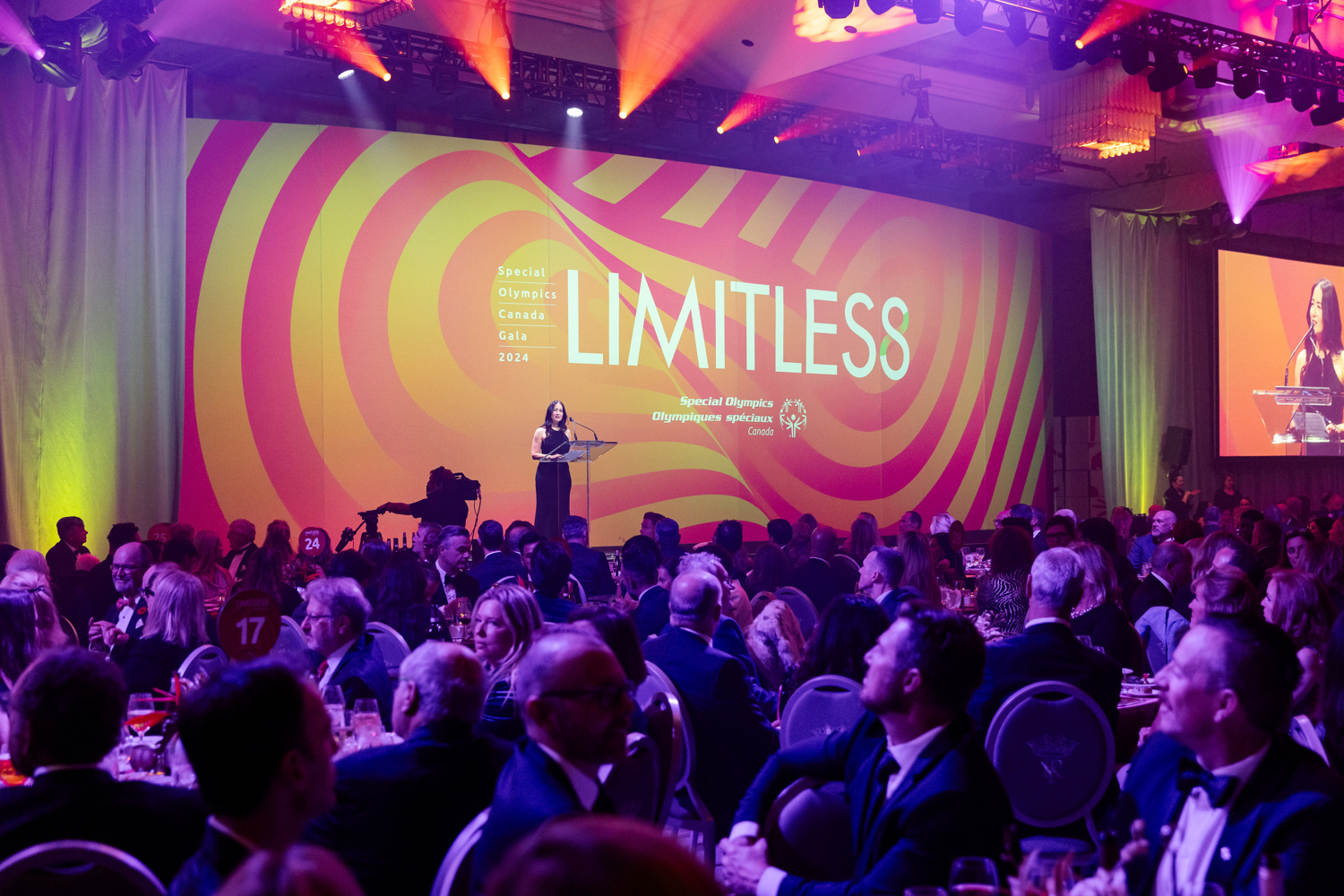Crowded room with a speaker on stage in front of a giant LIMITLESS sign