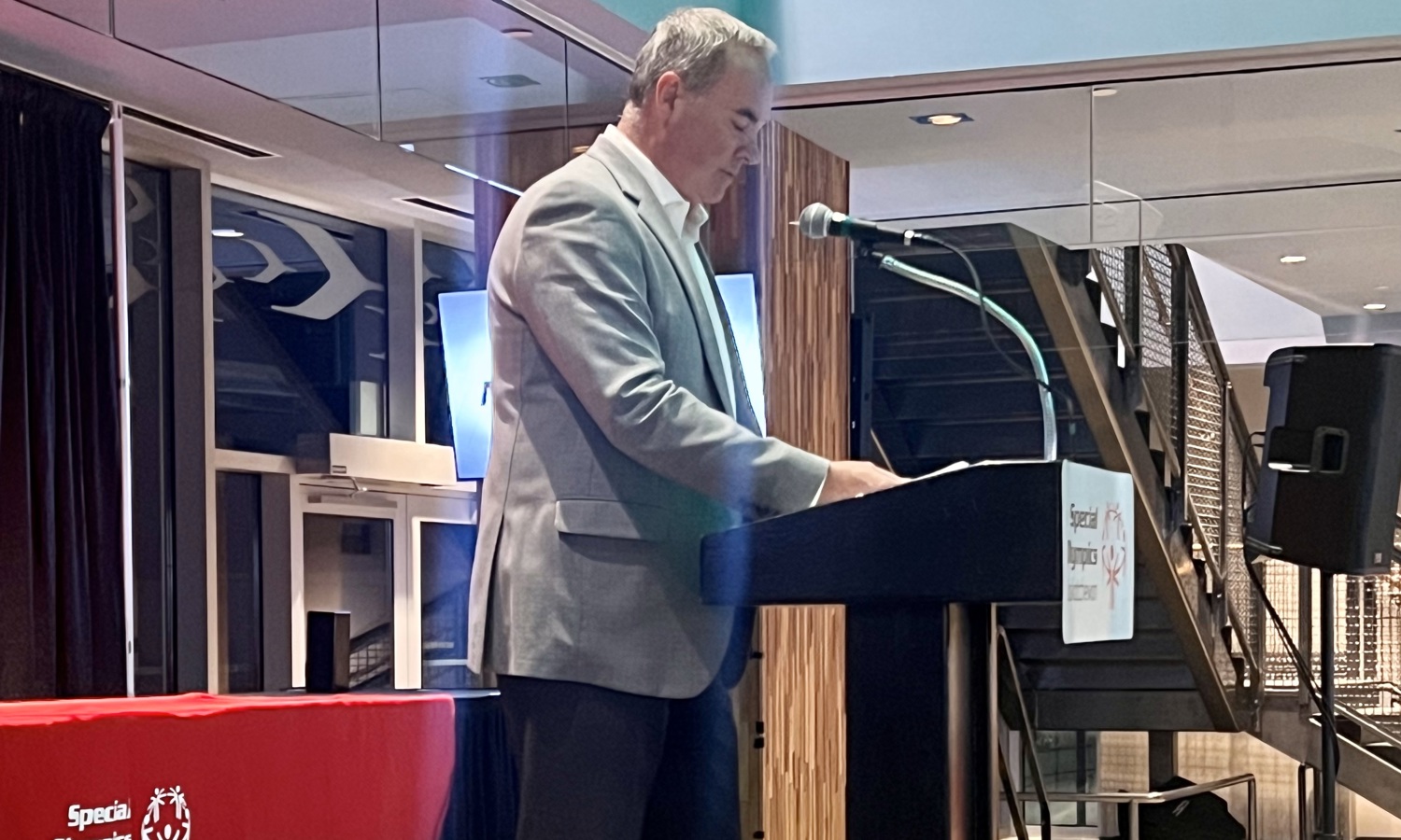 An individual is standing at a podium looking down at his speaker notes.