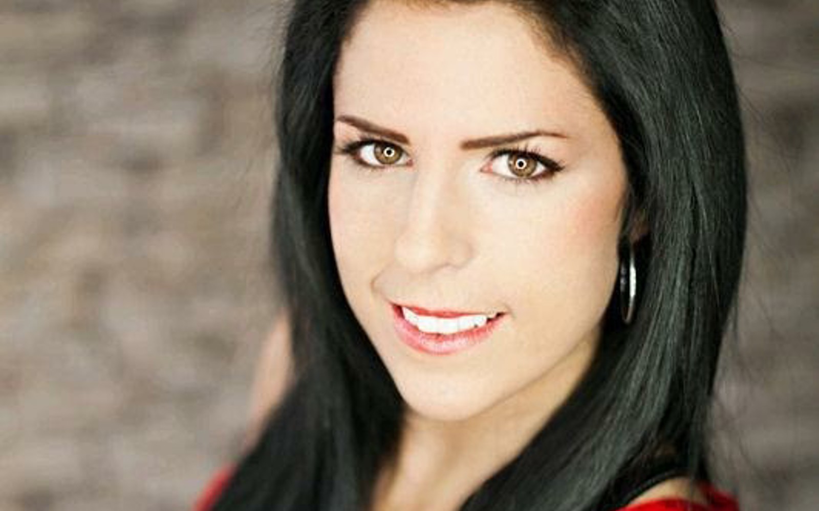Headshot of a woman with long dark hair wearing a red sleeveless blouse. 