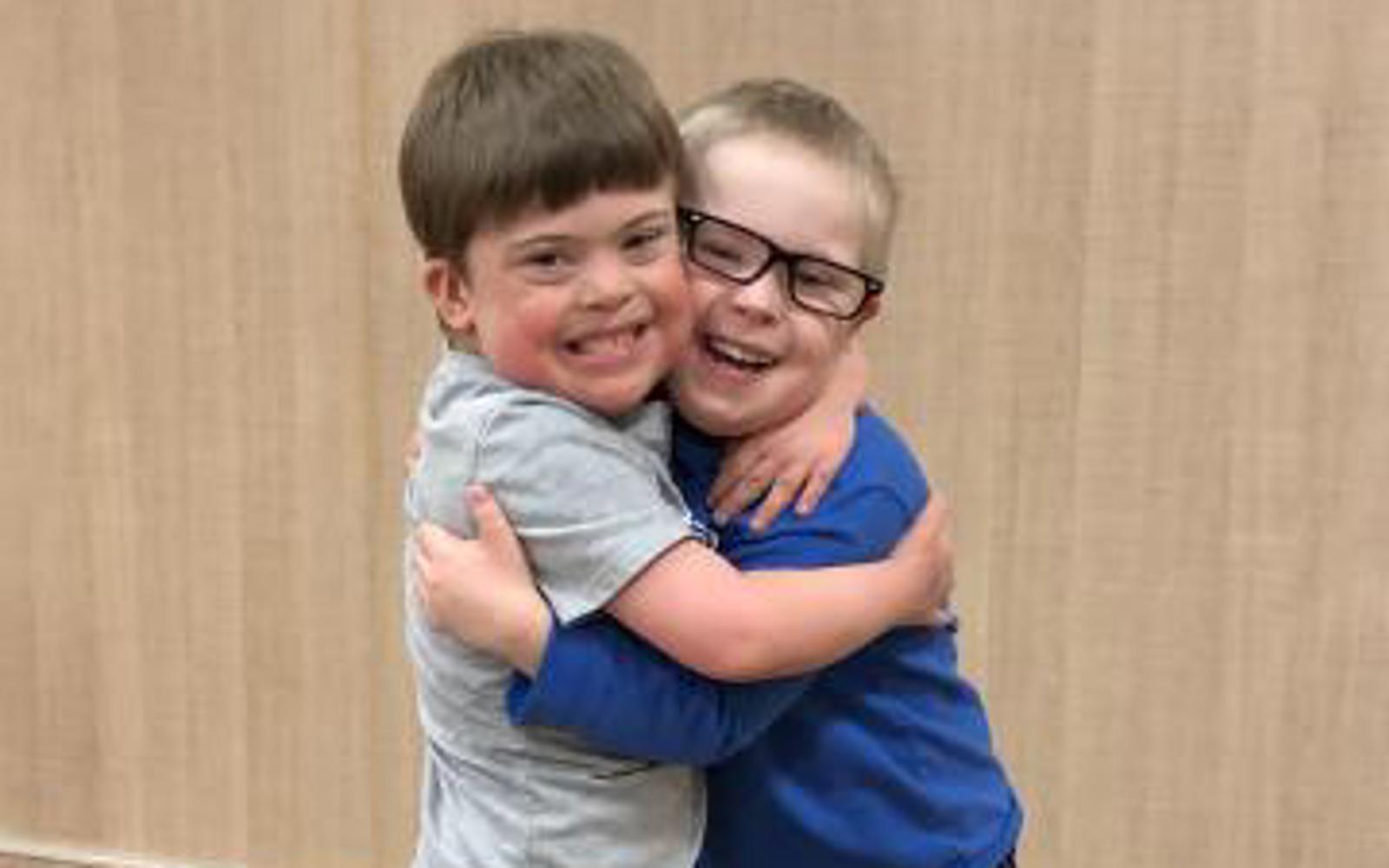 Two young athletes are hugging each other tightly and smiling for the camera.
