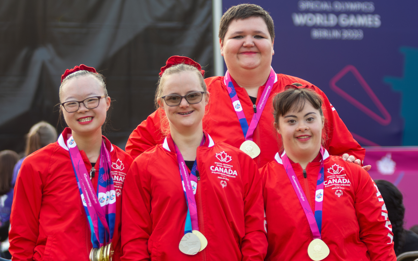 Four athletes in Team Canada uniforms with medals around their necks. 