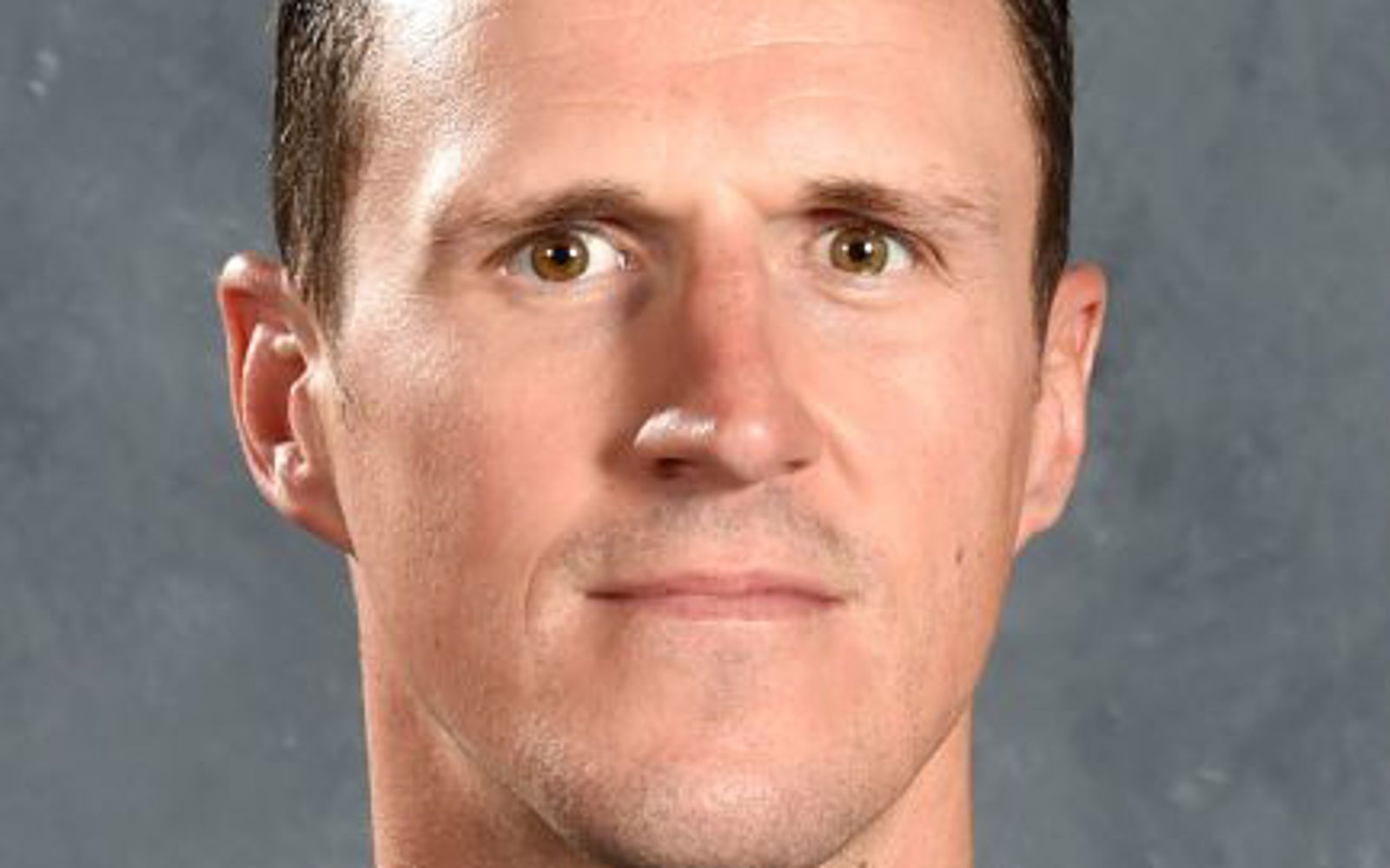 Man with dark hair wearing a hockey jersey. 