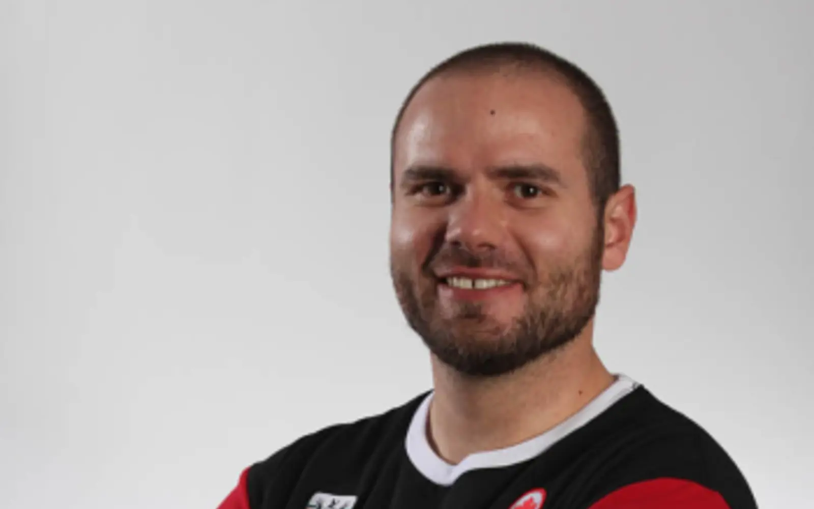 Portrait of a man with his arms crossed in a Team Canada Olympics tshirt. 