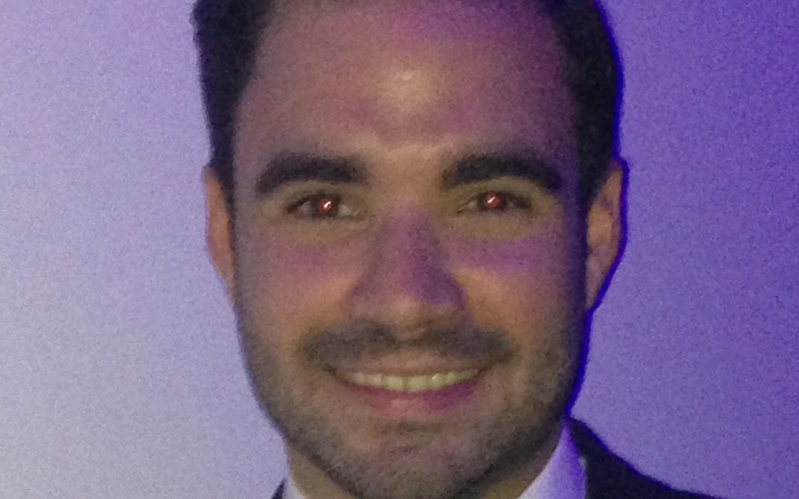 Headshot a man in a black jacket, white shirt and black bowtie. 