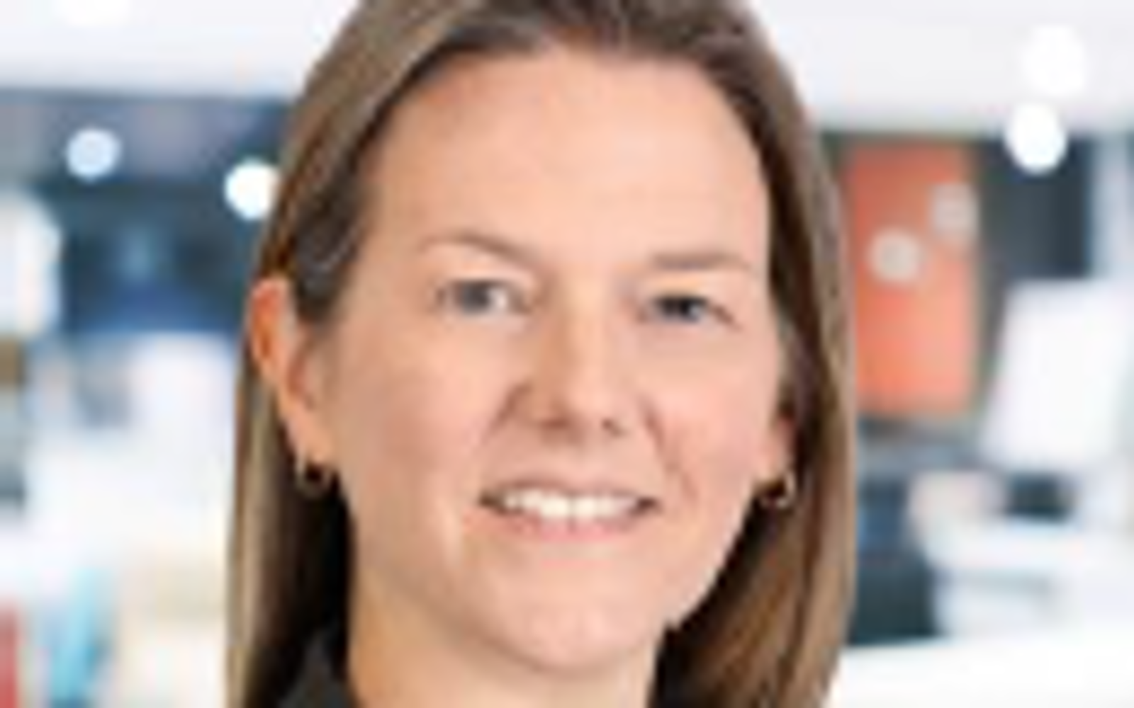 Woman with long blond hair wearing white dress shirt and black blazer. 